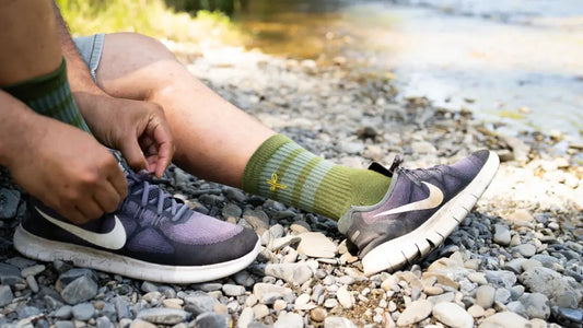 Do Better Colab organic cotton performance socks engineered for moisture wicking — man putting them on beside the river