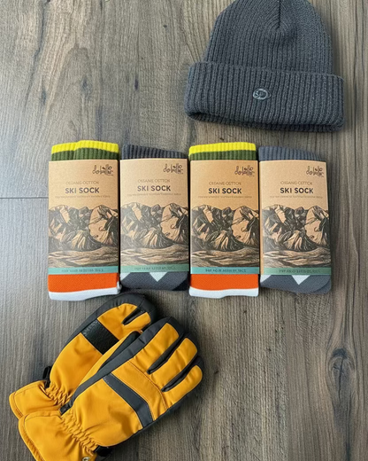 Four pairs of ski socks with packaging on a wooden surface