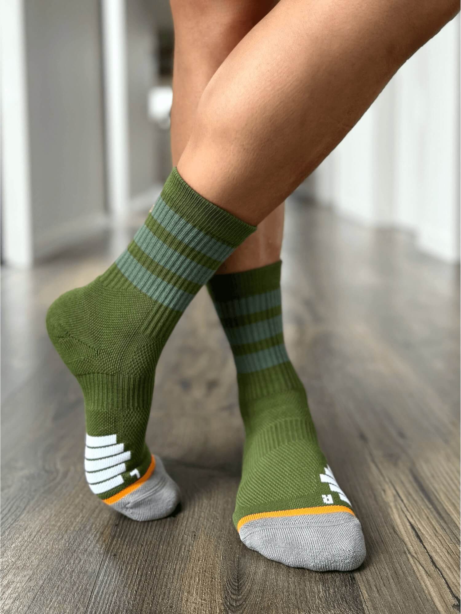 Organic cotton crew sports sock in forest green with orange, grey and white features.